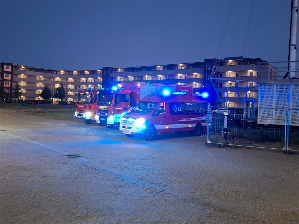 "Feuerwehr Kleve im Einsatz bei Gebäudebrand, Feuerwehrfahrzeuge und Einsatzkräfte vor dem brennenden Haus"