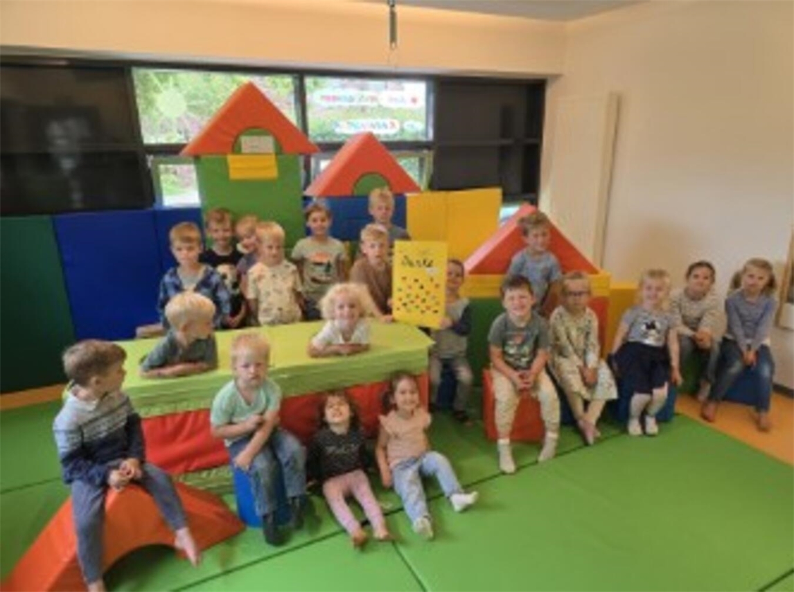 "Kindergarten Kieselstein Gebäude, bunte Spielgeräte im Außenbereich"