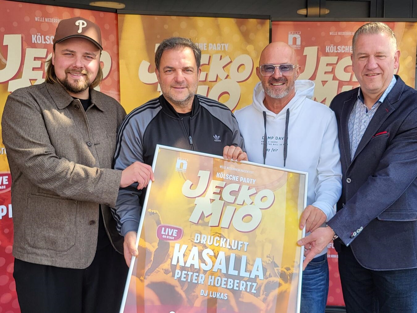 Vier Männer, darunter Martin Rütter, lächeln im Eisstadion Grefrath bei der Veranstaltung "Jeckomio".