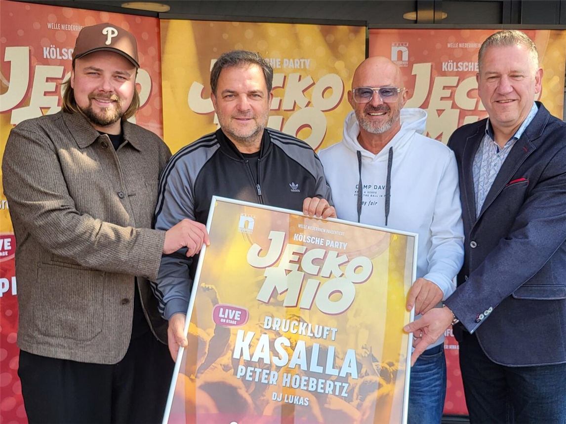 Vier Männer, darunter Martin Rütter, lächeln im Eisstadion Grefrath bei der Veranstaltung "Jeckomio".