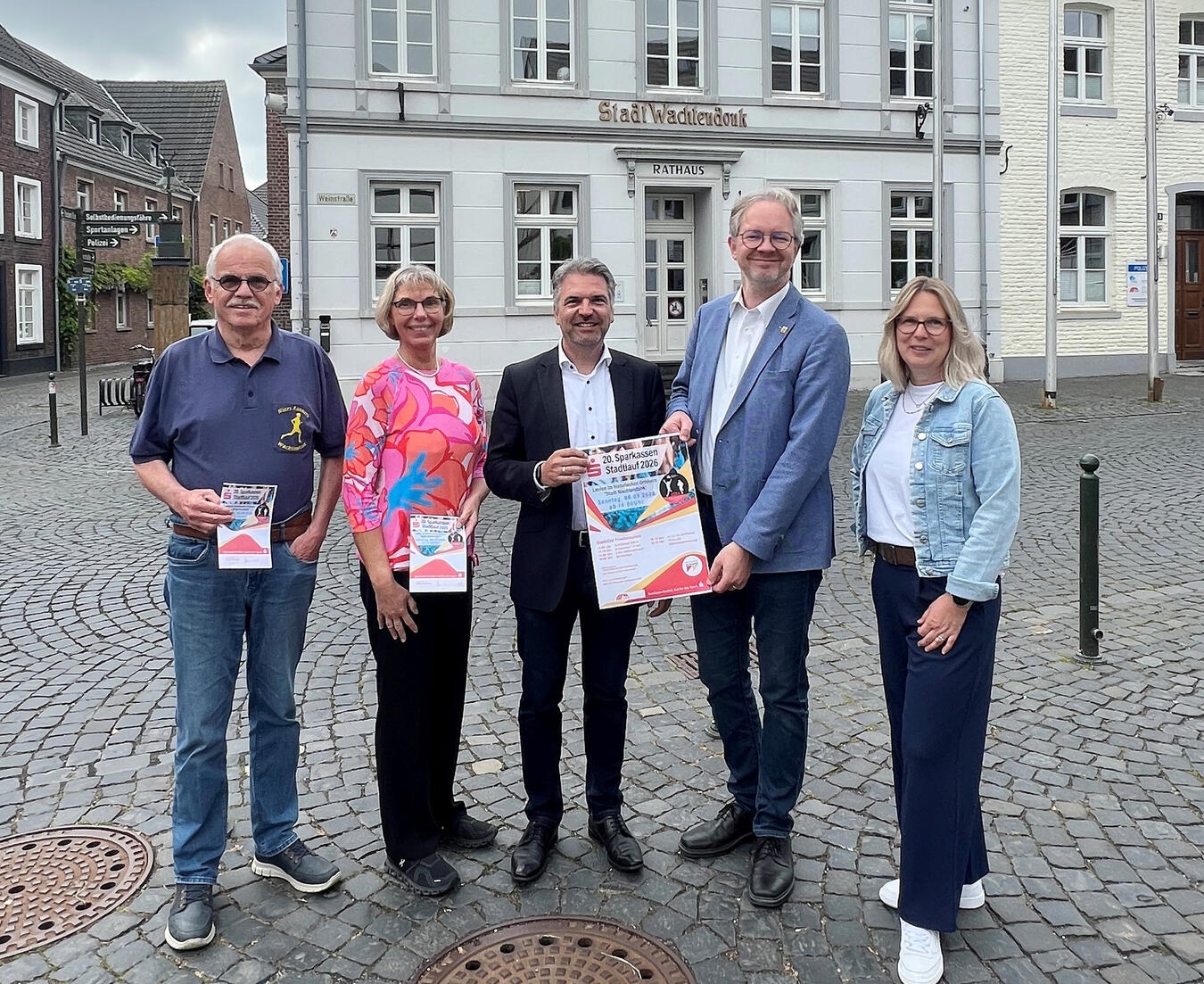 Gruppenfoto: Organisatoren des Sparkassen-Stadtlaufs Wachtendonk lächeln in die Kamera, darunter Vertreter der Sparkasse und Gemeinde.