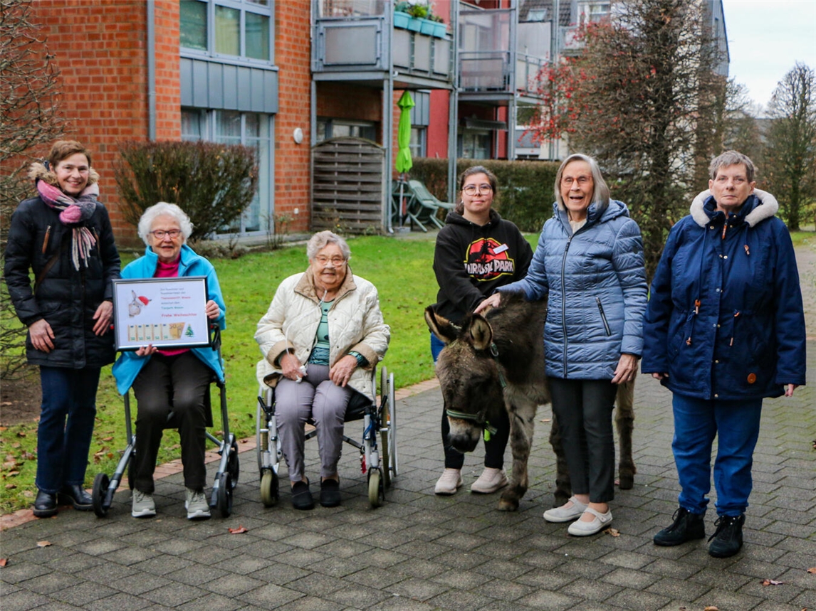 Freuen sich über die Spende und den Besuch von Esel Django: Isabel Tebartz-Janowitz vom Tierpark (links) und die Bewohner des Theresien-Stifts. Foto: Caritasverband Geldern-Kevelaer