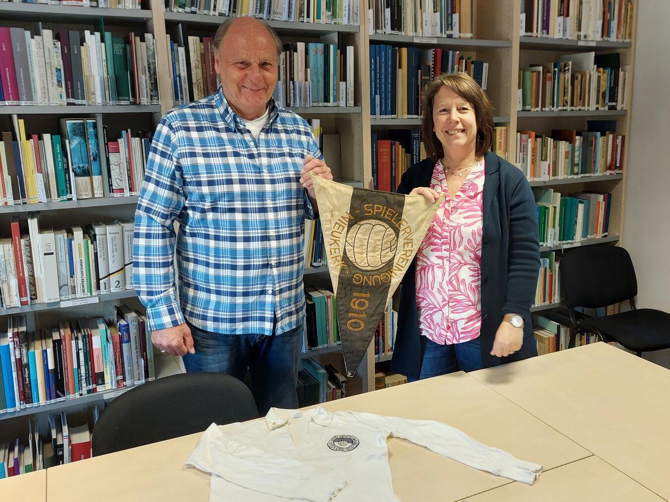 Friedhelm Messinger und Gemeindearchivarin Nicole Sillekens mit dem historischen Wimpel und dem Fußballtrikot der Spielervereinigung 1910 Nieukerk.Foto: Gemeindearchiv Kerken