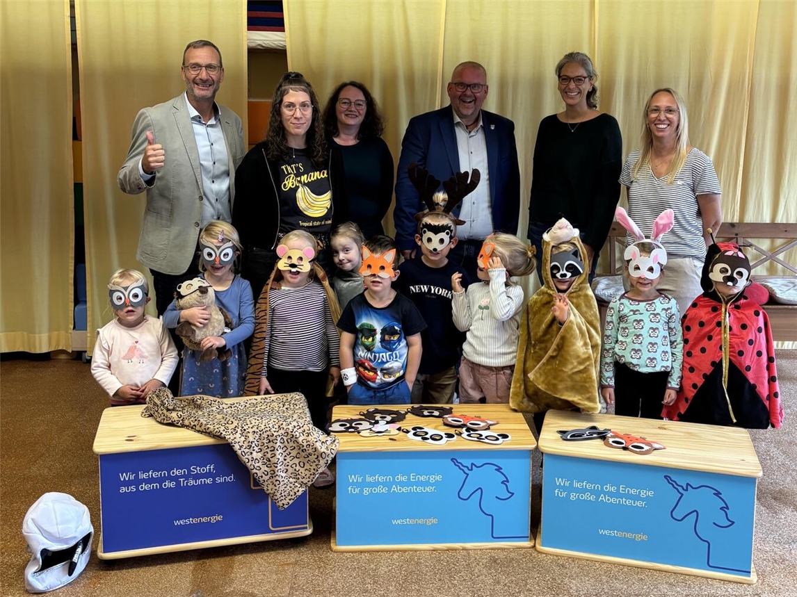 Frithjof Gerstner (Westenergie-Kommunalmanager), Pia Schäfer (stellvertretende Leitung Kita Fliegenpilz), Stefanie Scholle (Leitung Kindergarten St. Nikolaus), Bürgermeister Dirk Ketelaers, Dorothea Gräfen (Erzieherin Kita Fliegenpilz) und Ute Müller (Leitung Kita St. Hubertus) freuen sich gemeinsam mit den verkleideten Kindern über die neuen Theaterkisten. Foto: privat