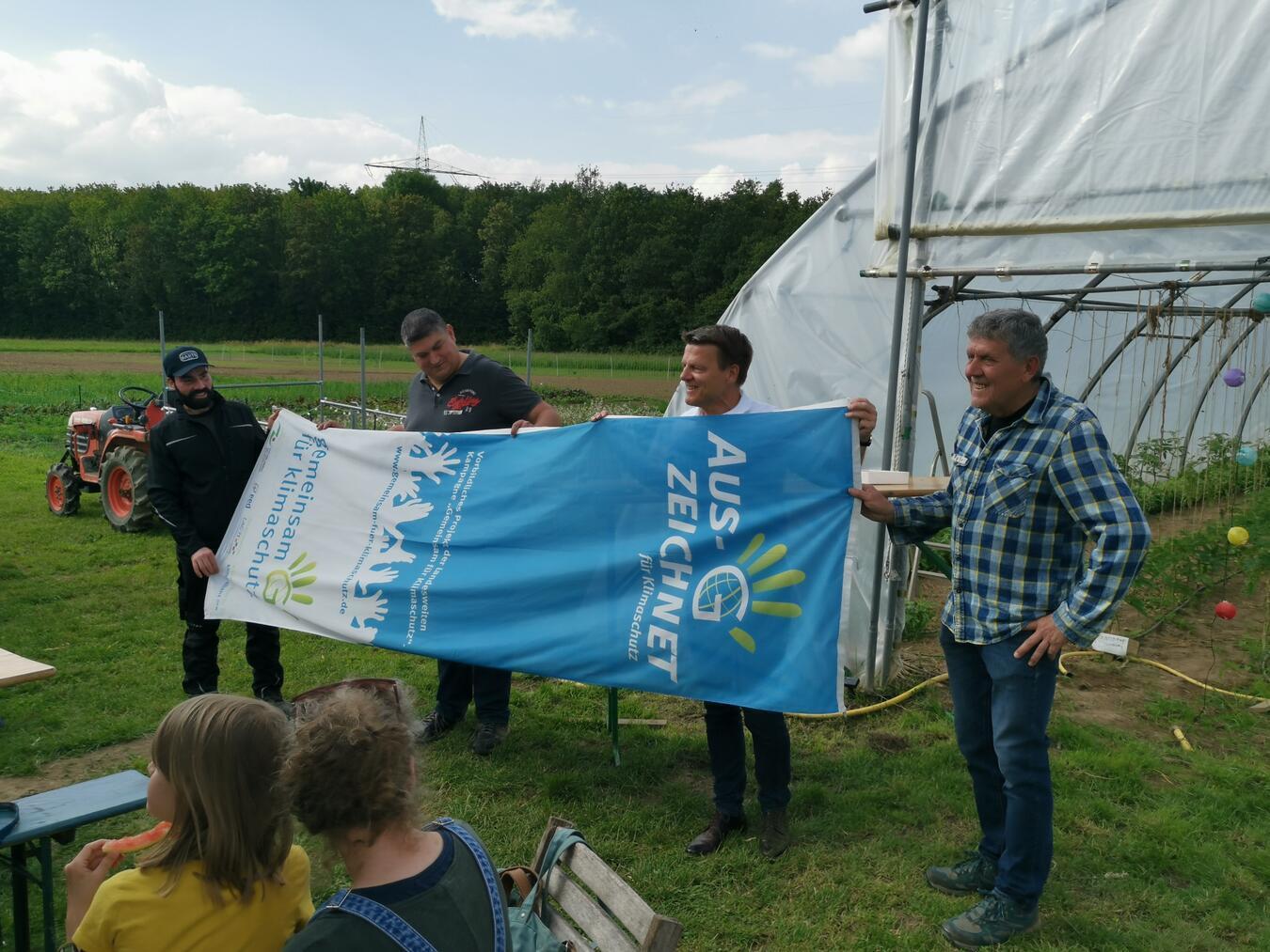 Gärtner Abdul Darwashi, Gründungsmitglied und Kassenwart Martin Römer, Bürgermeister Dirk Haarmann sowie Gründungsmitglied und Vorstand Peter Langer bei der Übergabe der Klimaschutzflagge an die Solawi Niederrhein. Foto: Solawi Niederrhein