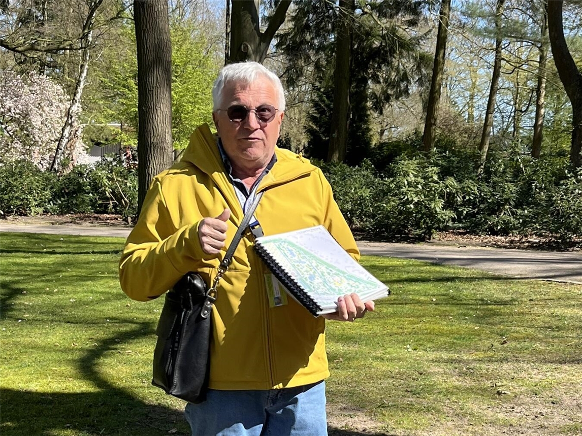 "Porträt von Gartenexperte Hans Heinz Hübers im grünen Garten, lächelnd in die Kamera."