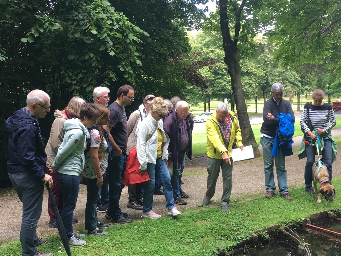 "Gartenführer Hans Heinz Hübers leitet Besuchergruppe durch gepflegte Gartenanlagen"