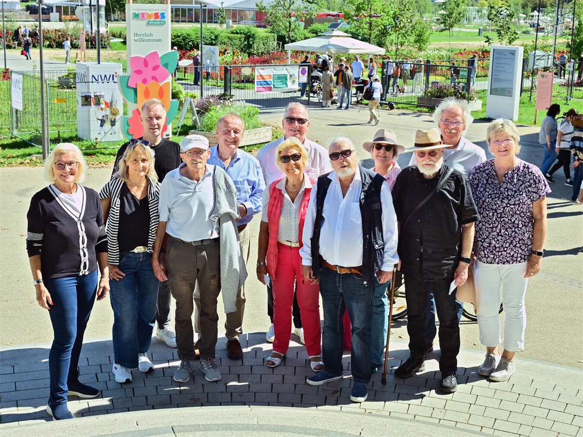 Mitglieder von Presseclubs besuchen Landesgartenschau Neuss; Sigrid Baum im Gespräch mit Kollegen, grüne Kulisse im Hintergrund.