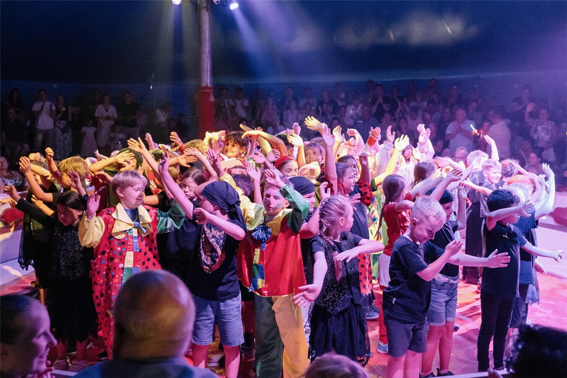 Kinder üben Zirkuskunststücke mit Profis, verwandeln sich in Artisten, Zirkusprojekt, Kinderzirkus, Artistentraining.