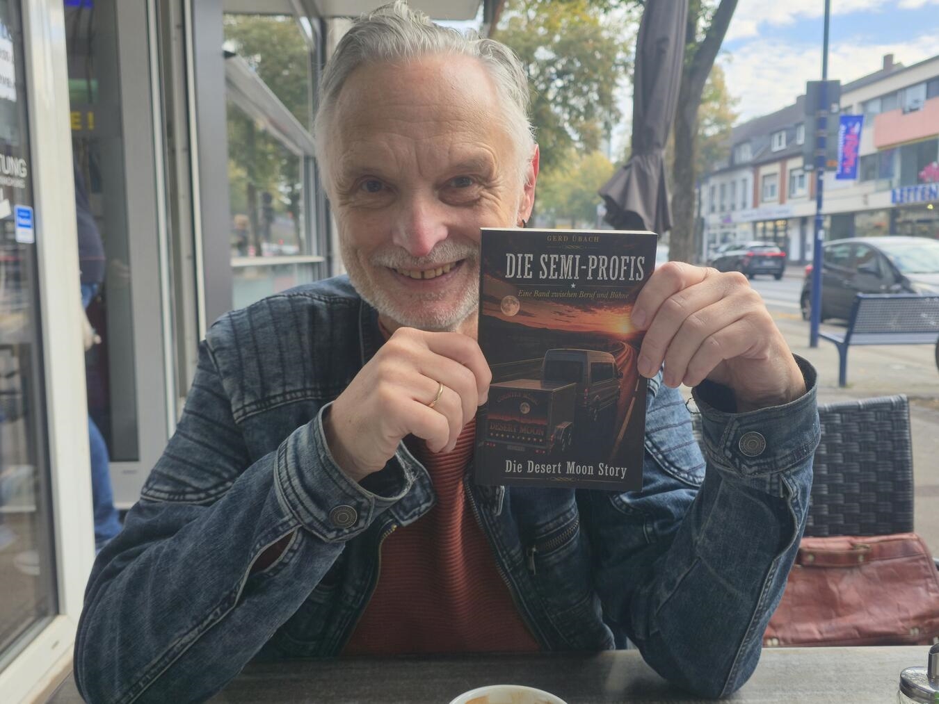 Gerd Übach hält sein Buch über die Band „Desert Moon“ in der Hand. Foto von NN.