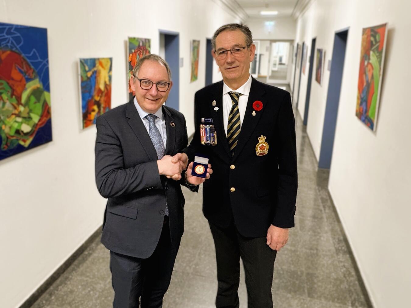 Gerrit Bruggink (re.) übergibt die Gedenkmedaille als Zeichen des Gedenkens und der Freundschaft an den Reeser Bürgermeister Sebastian Hense. Foto: Stadt Rees