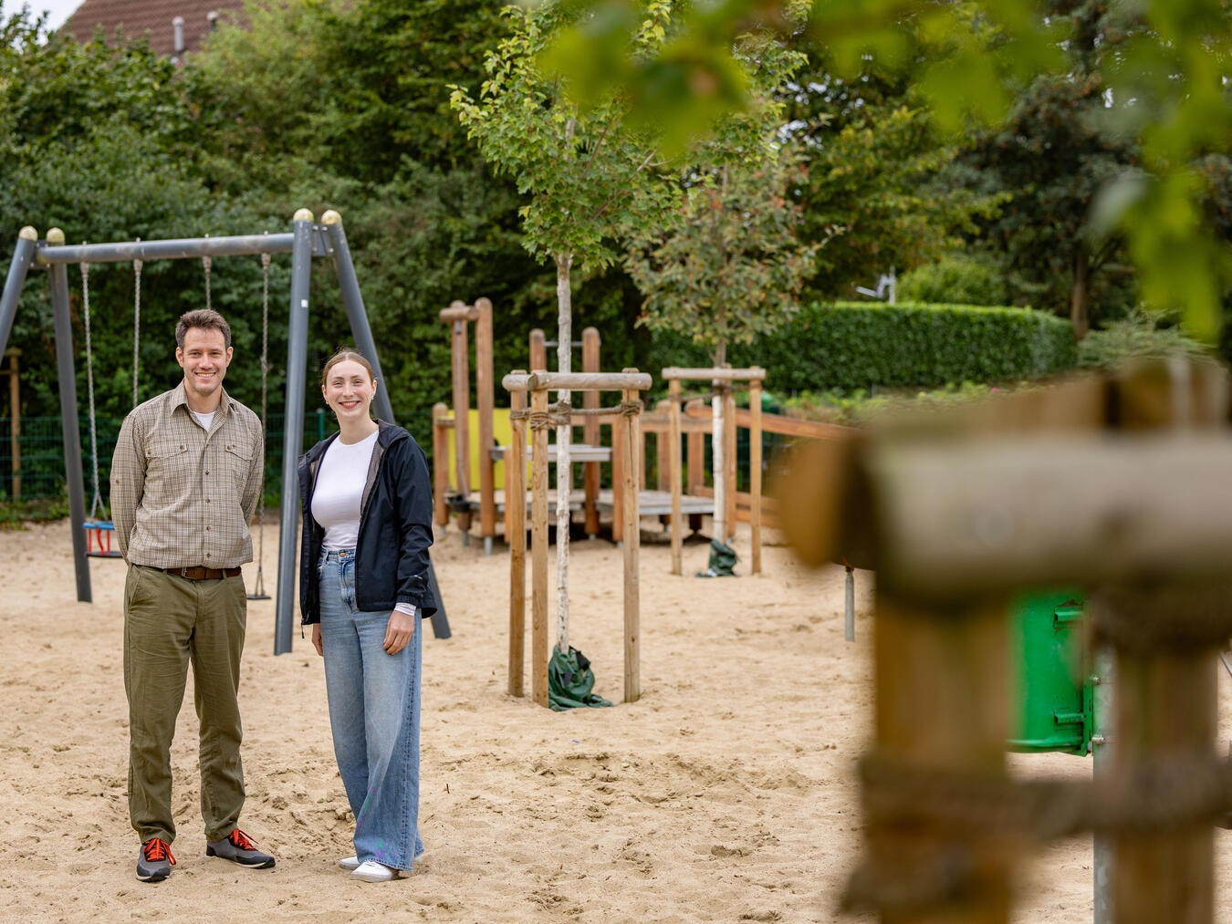 "Michael Verfürth und Merle Gemke auf dem Spielplatz Hüfgen, umgeben von jungen Bäumen, Kleve"