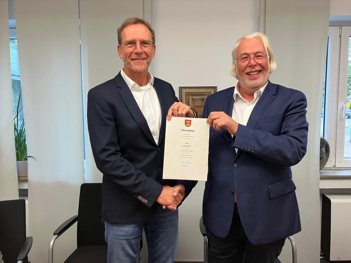 Guido Miesen (links) wird von Bürgermeister Ferdi Böhmer für sein 25-jähriges Dienstjubiläum bei der Gemeinde Kranenburg geehrt. Foto: Gemeinde Kranenburg
