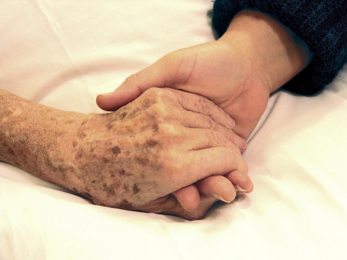 "Zwei Personen halten Hände bei Infotag ‚Gemeinsam bis zuletzt‘, organisiert vom Caritasverband Geldern-Kevelaer."