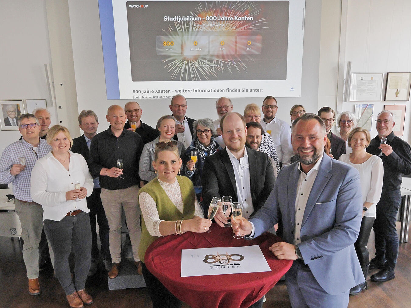Hannah Müller (TIX), Stadtarchivar Lukas Petzold und Xantens Bürgermeister Rafael Zur (vorne v.l.) sowie Vertretende der Ratsfraktionen, der TIX und der Fachbereiche haben schonmal gemeinsam auf den Start der Planungen angestoßen. NN-Foto: Theo Leie