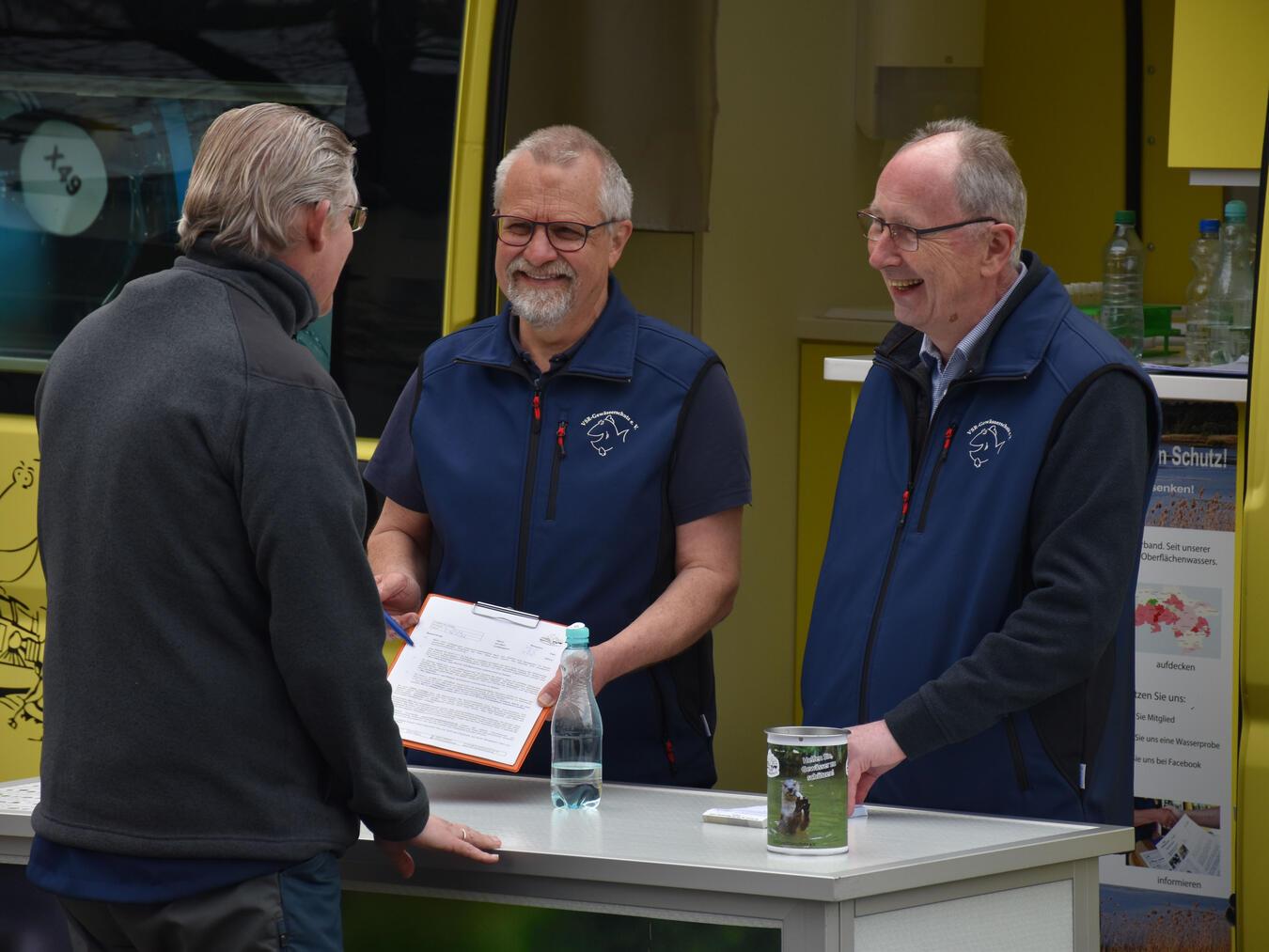 Harald Gülzow (m.) und Ehrenamtler Heinz Wilhelm Hülsmans (r.) beraten einen Brunnennutzer am Labormobil vom VSR-Gewässerschutz. Foto: VSR/Susanne Bareiß-Gülzow