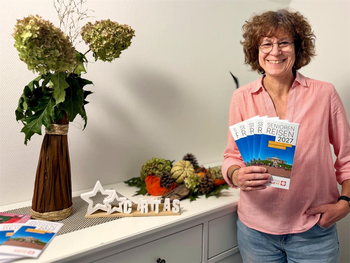 Heike Lippe präsentiert Caritas-Seniorenreisen Programmhefte im Büro. Foto: CV Kleve