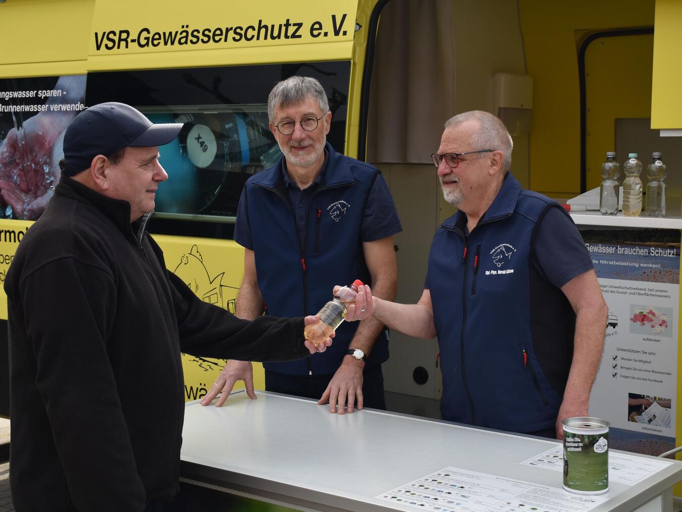 Ist das Brunnenwasser okay? Heinz-Theo van Wickeren und Harald Gülzow nehmen eine Wasserprobe entgegen. Foto: Ruben Witsch
