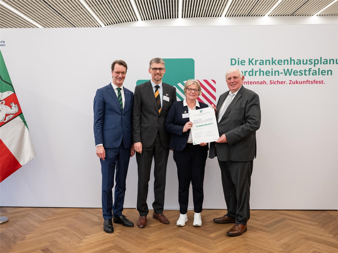 Hendrik Wüst, Ministerpräsident des Landes Nordrhein-Westfalen, Karl-Ferdinand von Fürstenberg, Geschäftsführer des Marien-Hospitals Wesel, Dr. med. Stephanie Boßerhoff, Chefärztin des Sozialpädiatrischen Zentrums (SPZ) am Marien-Hospitals Wesel, und Karl-Josef Laumann, Minister für Arbeit, Gesundheit und Soziales des Landes Nordrhein-Westfalen, mit dem Förderbescheid. Foto: Land NRW / Mark Hemenau