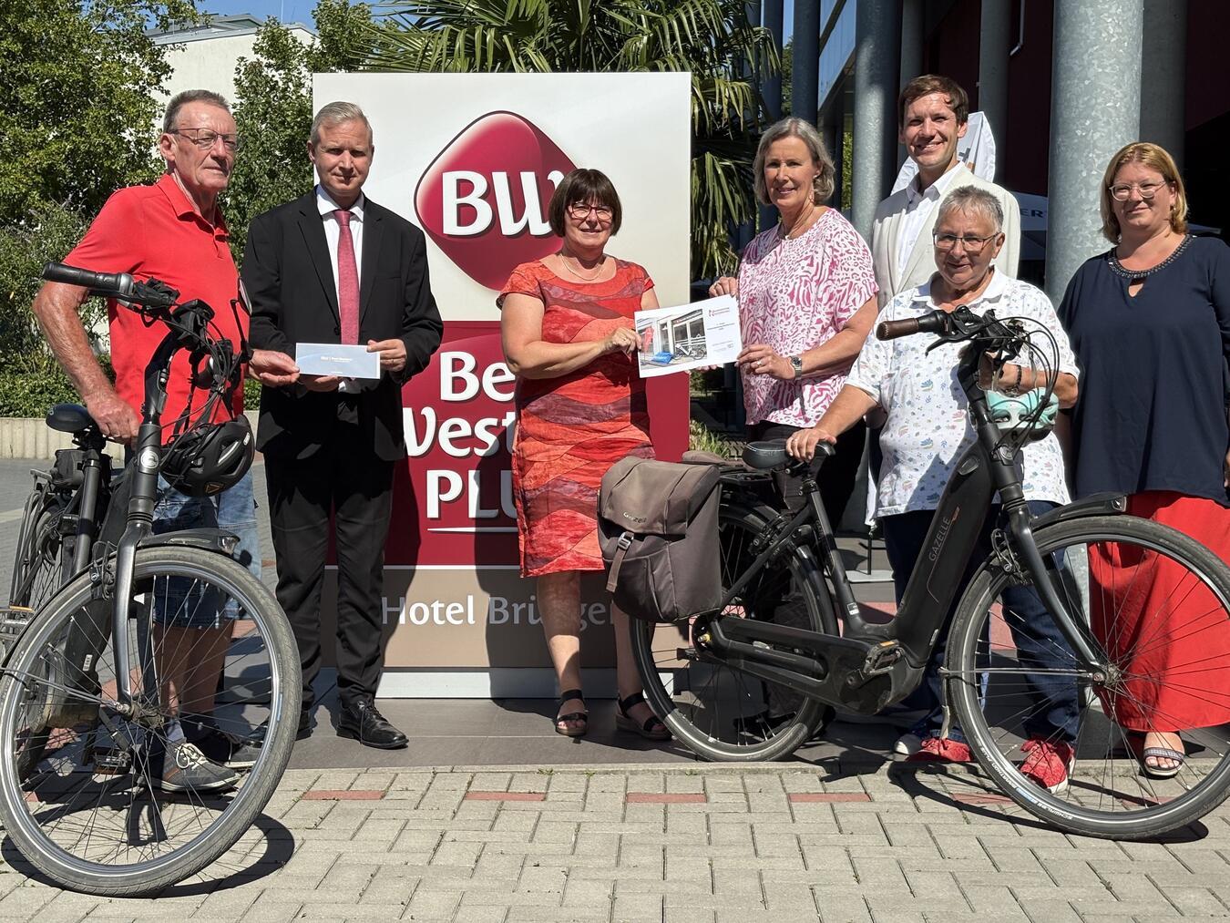 Herzlichen Glückwunsch: Auf Ursula von den Bruck (4.v.r.) wartet ein neues Tourenrad. Herbert Linges (l.), der mit Ehefrau Anita (2.v.r.) nach Brüggen geradelt war, erhielt einen Hotel-Gutschein. Mit ihnen freuten sich (v.l.): René Maludy (Best Western Plus Hotel), Brigitte Odinius (WFG), Matthias Peters (NEW) und Nina Jörgens (NT). Foto: NT