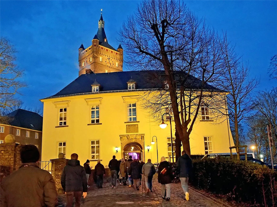 "Menschen singen im festlichen Innenhof der Schwanenburg zur Vorweihnachtszeit"