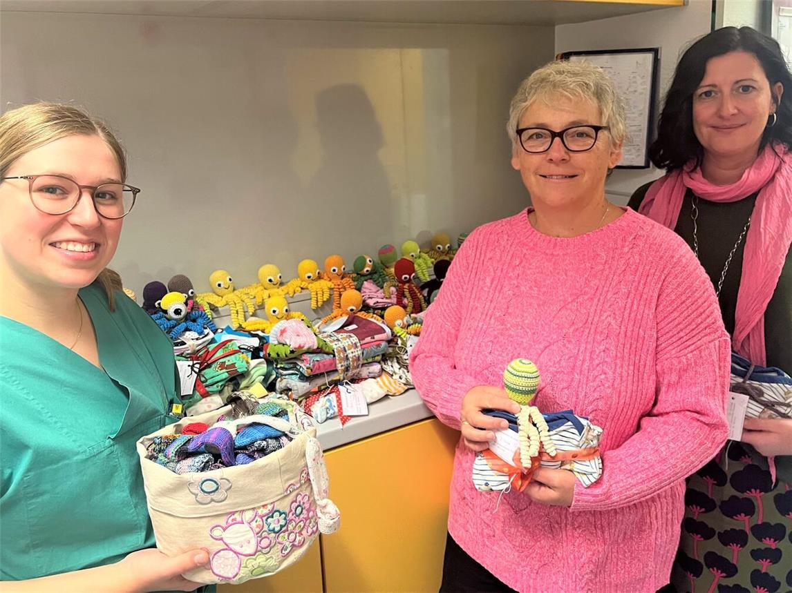 Jacqueline Killemann (l.), Pflegefachkraft mit pädiatrischer Vertiefung auf der Intensivstation für Früh- und Neugeborene der Klinik für Kinder und Jugendliche im St.-Clemens-Hospital, nimmt die 300 bunten und gespendeten Handarbeiten von Sonja Martens und Jessica Döhrn (r.) von der Initiative Helfen mit Herz aus Goch entgegen.Fotos: St.-Clemens-Hospital