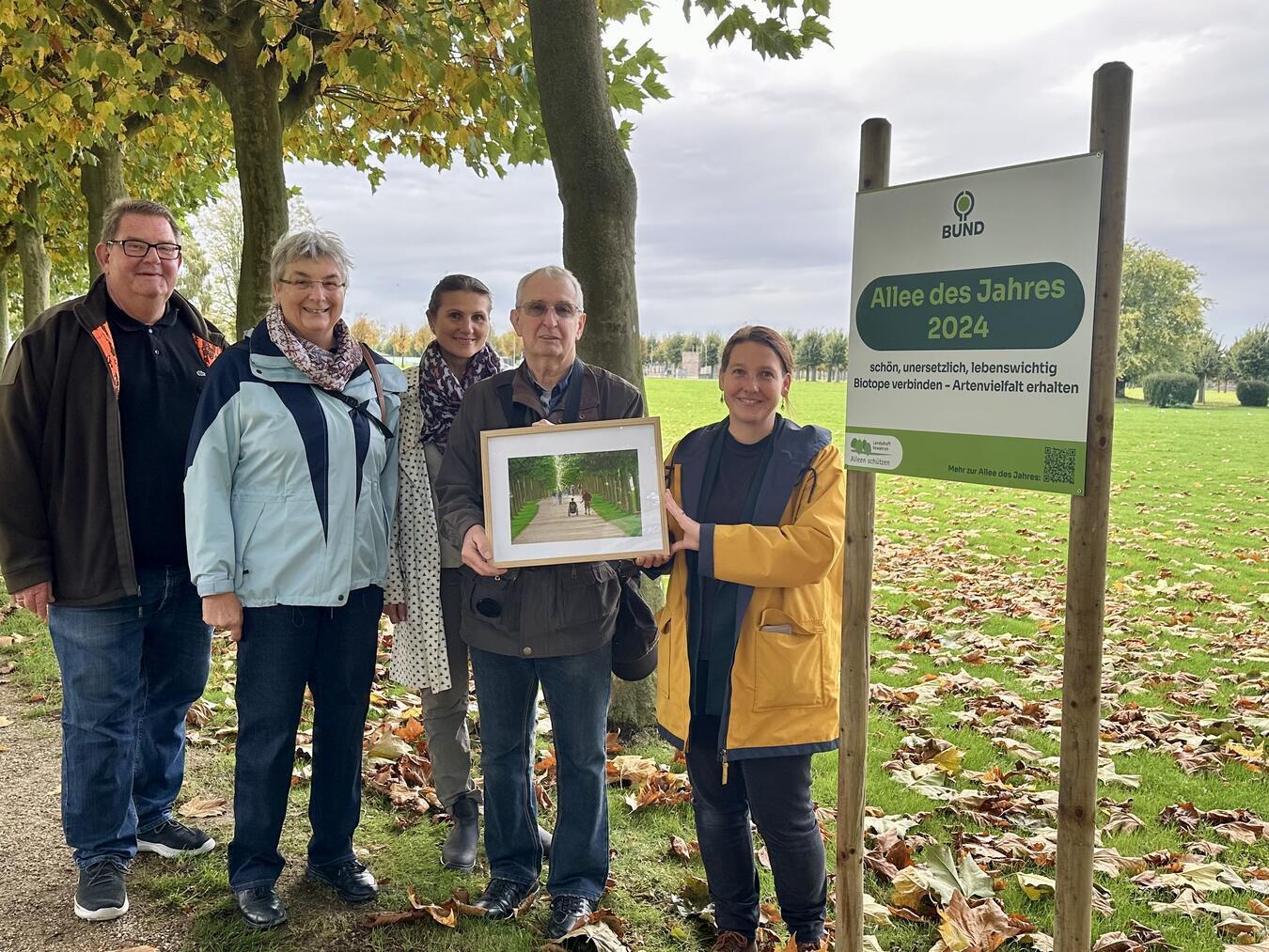 Jasmin Personn (r.) überreichte Jürgen Guhlke (2.r.) und APX-Leiter Martin Müller (l.) nicht nur das Gewinner-Bild, sondern auch ein Schild, dass die „Allee des Jahres“ ausweist. NN-Foto: SP