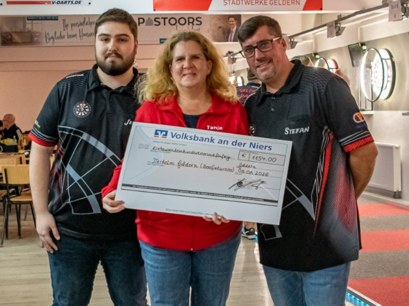Darts-Turnier in Geldern unterstützt das Tierheim Jerome Liedtgens und Stefan Pricken überreichen Tanja Großmann einen Scheck für den Tierschutzverein Geldern.