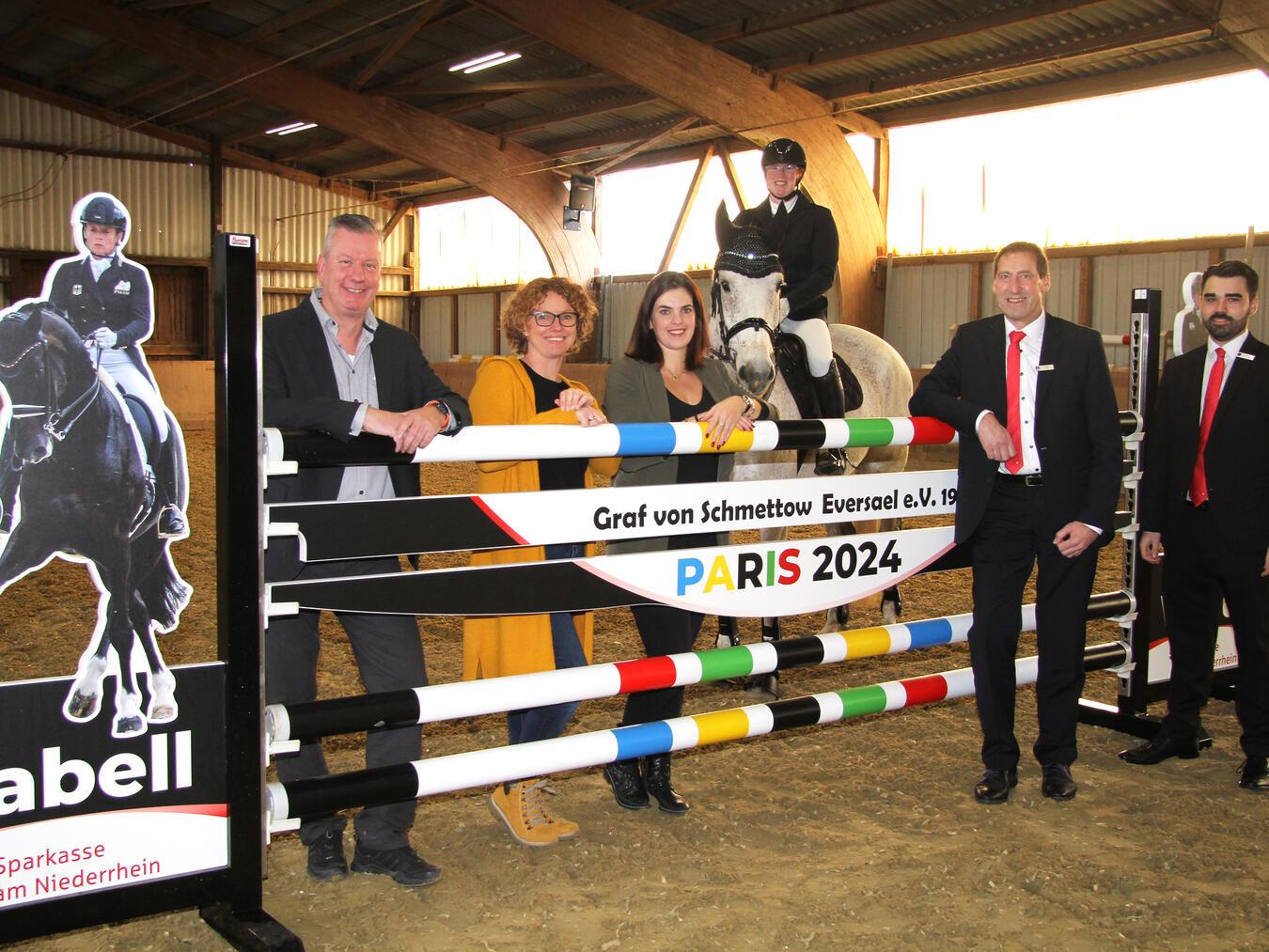 Jörg Gierling, Anja Harting und Luisa Nederkorn vom Reit- und Fahrverein Graf von Schmettow Eversael bedanken sich bei Norbert Kubik und Nils Schwenner von der Sparkasse am Niederrhein. Die ermöglichte mit einer 3.000-Euro-Spende die Anfertigung eines neuen Sprungs zu Ehren von Isabell Werth. Darüber freut sich auch Tanja Lechsner auf dem neunjährigen Flash. Foto: Sparkasse am Niederrhein
