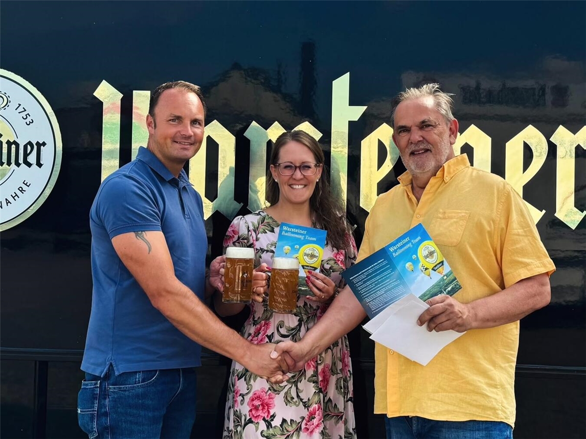 "Johannes Pieper gratuliert Fabian und Katja Piperek zum Gewinn, lächelnd bei einer Preisverleihung."