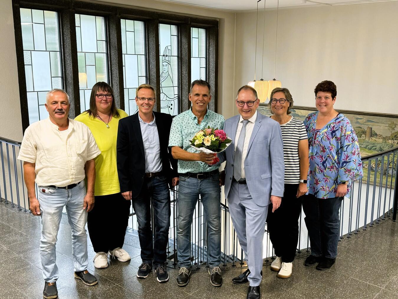 Jubiläum für den Schulhausmeister: Klaus Sesing (Mitte) mit (v. li.) Thomas Jander, Schulhausmeister Lindenschule Mehr, Eva van Eenennaam, Sekretärin an den Grunschulen in Millingen und Mehr, Rainer Janßen, stellvertretender Fachbereichsleiter Zentrale Dienste, Sebastian Hense, Bürgermeister Rees, Elke Strede, Fachbereichsleiterin Planen, Bauen und Umwelt sowie Barbara Peerenboom, Personalrat Stadtverwaltung. Foto: Stadt Rees