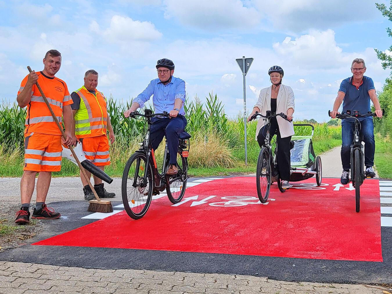 Kaum zu übersehen: Die rote Fahrbahnmarkierung signalisiert die „Bevorrechtigung“ von Radfahrern wie Bürgermeister Sebastian Hense, Stephanie Schlebusch und Georg Messing (v. l.) auf dem Planetenradweg. Drei bis vier Stunden haben Patrick Terwey-Altenhövel (l.), Thomas Pohle (2. v. l.) und ihre Kollegen des Reeser Bauhofs je Überquerung, wie hier an der Wilhelmstraße, benötigt. NN-Foto: MB