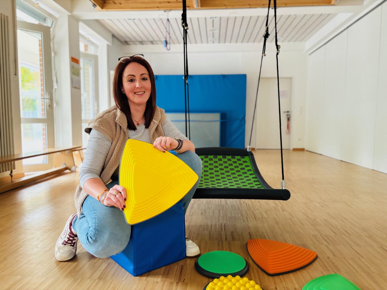 Jung, engagiert, ganzheitlich Kita-Leiterin Jannine van Dülmen mit den neuen Flusssteinen in der Turnhalle des Familienzentrums Zauberstern in Kleve. Foto: Caritas