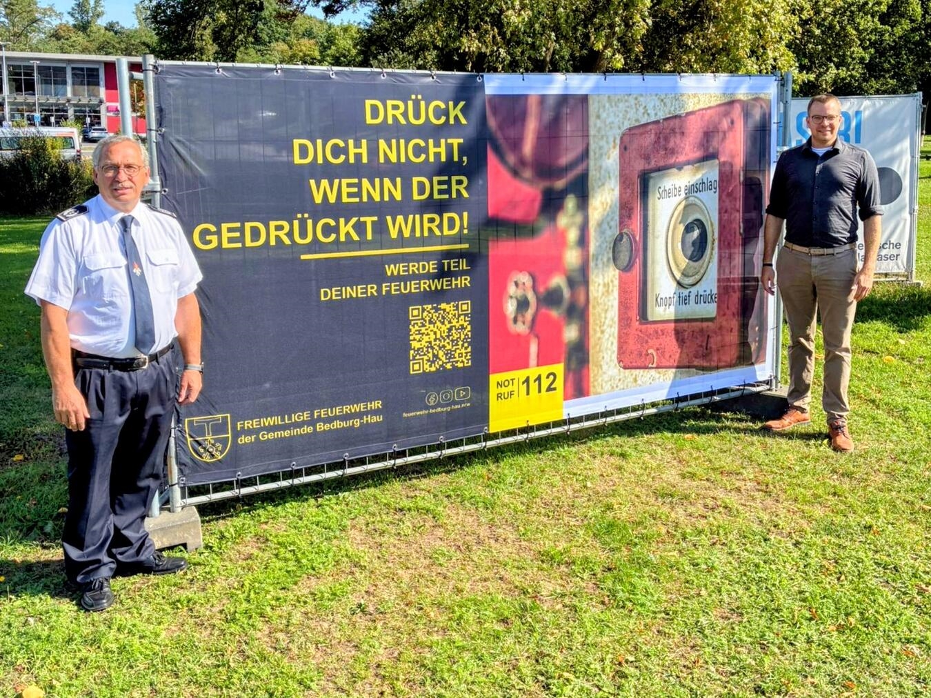 Klaus Elsmann (links), Leiter der Freiwilligen Feuerwehr Bedburg-Hau, und Bürgermeister Stephan Reinders enthüllten gemeinsam das neue Banner, mit dem die Feuerwehr um neue Mitglieder wirbt. Foto: Feuerwehr Bedburg-Hau