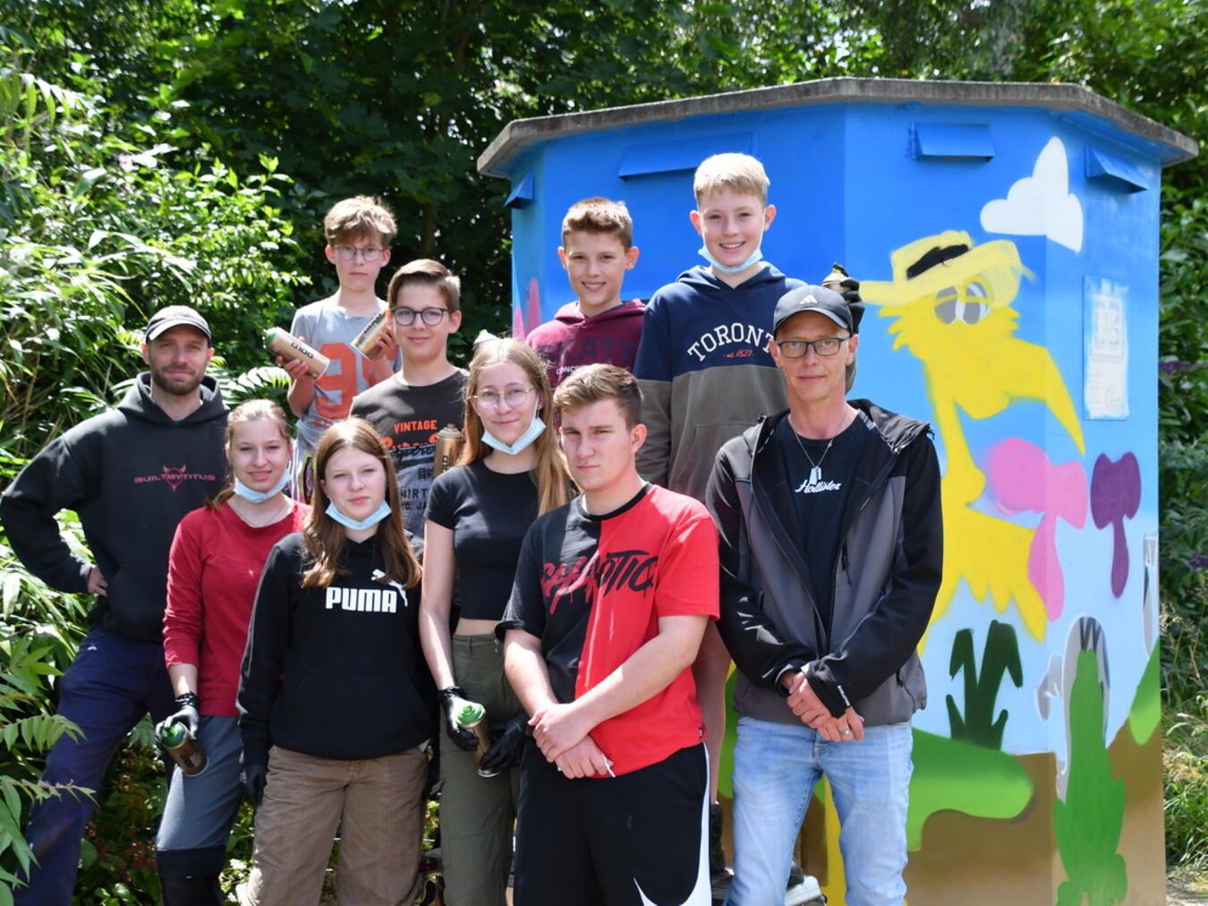Künstler Mathias te Poel (links), Holger Keßler vom Jugendfreizeitheim „Päpp“ (rechts) und die Jugendlichen vor ihrem Kunstwerk. Foto: Gemeinde Kranenburg