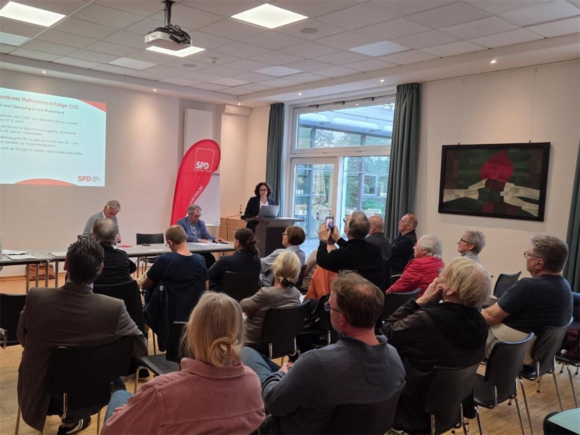 "SPD Kleve Mitglieder diskutieren engagiert über Parteikurs bei Versammlung, Gruppenfoto im Konferenzraum"