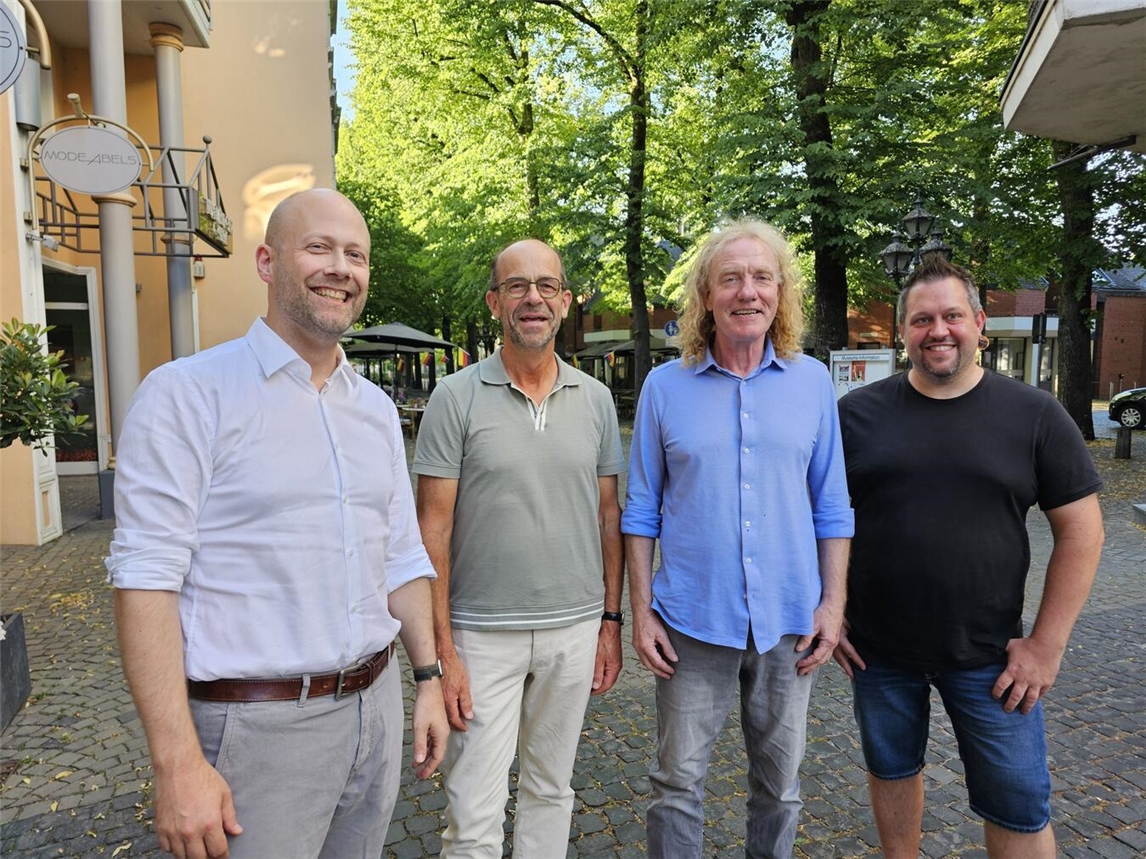 Vier Männer, darunter Tobias Kocken, beim Herbstfest in Kevelaer, posieren lächelnd vor einem Geschäft.