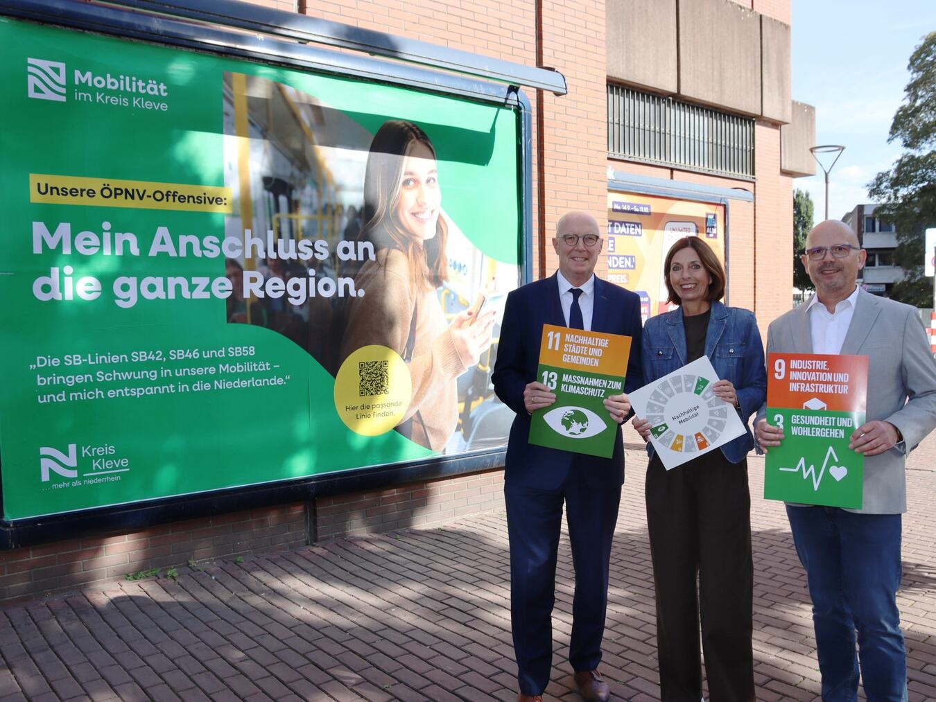 Landrat Christoph Gerwers und Team werben in Kleve für ÖPNV-Kampagne und UN-Nachhaltigkeitsziele vor Plakat.