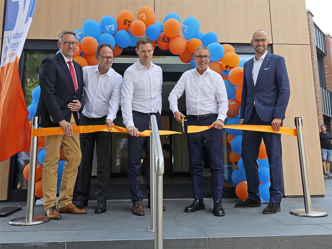 Landrat Ingo Brohl, Volksbank-Vorstandsmitglied Dieter Hackstein, Vorstandsmitglied Jan Hußmann, Vorstandvorsitzender Guido Lohmann und Alpens Bürgermeister Ludger Staymann beim Durchschneiden des symbolischen orangen Bandes als Zeichen der Wiedereröffnung. NN-Foto: Theo Leie