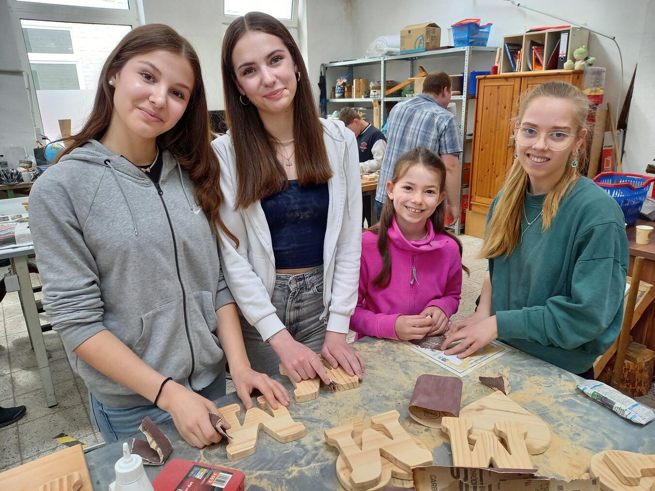 Lina, Philomena und Maja unterstützen Hella (2.vr.) in einem Projekt im Fairkaufhaus dabei ein Muttertagsgeschenk zu basteln