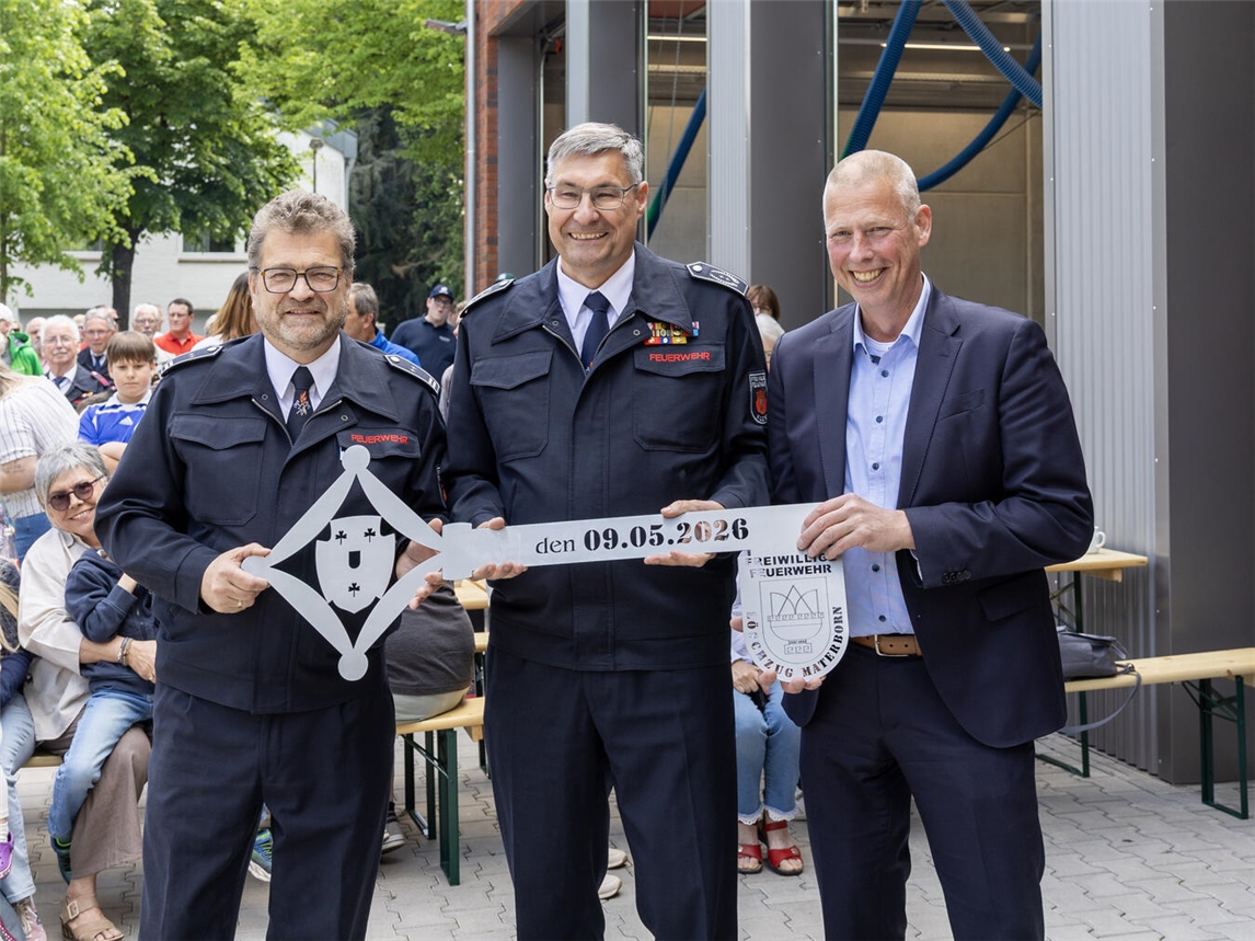 "Löschzugführer Ernst Vehreschild, Feuerwehrleiter Ralf Benkel und Bürgermeister Markus Dahmen bei Schlüsselübergabe vor Feuerwehrhaus"