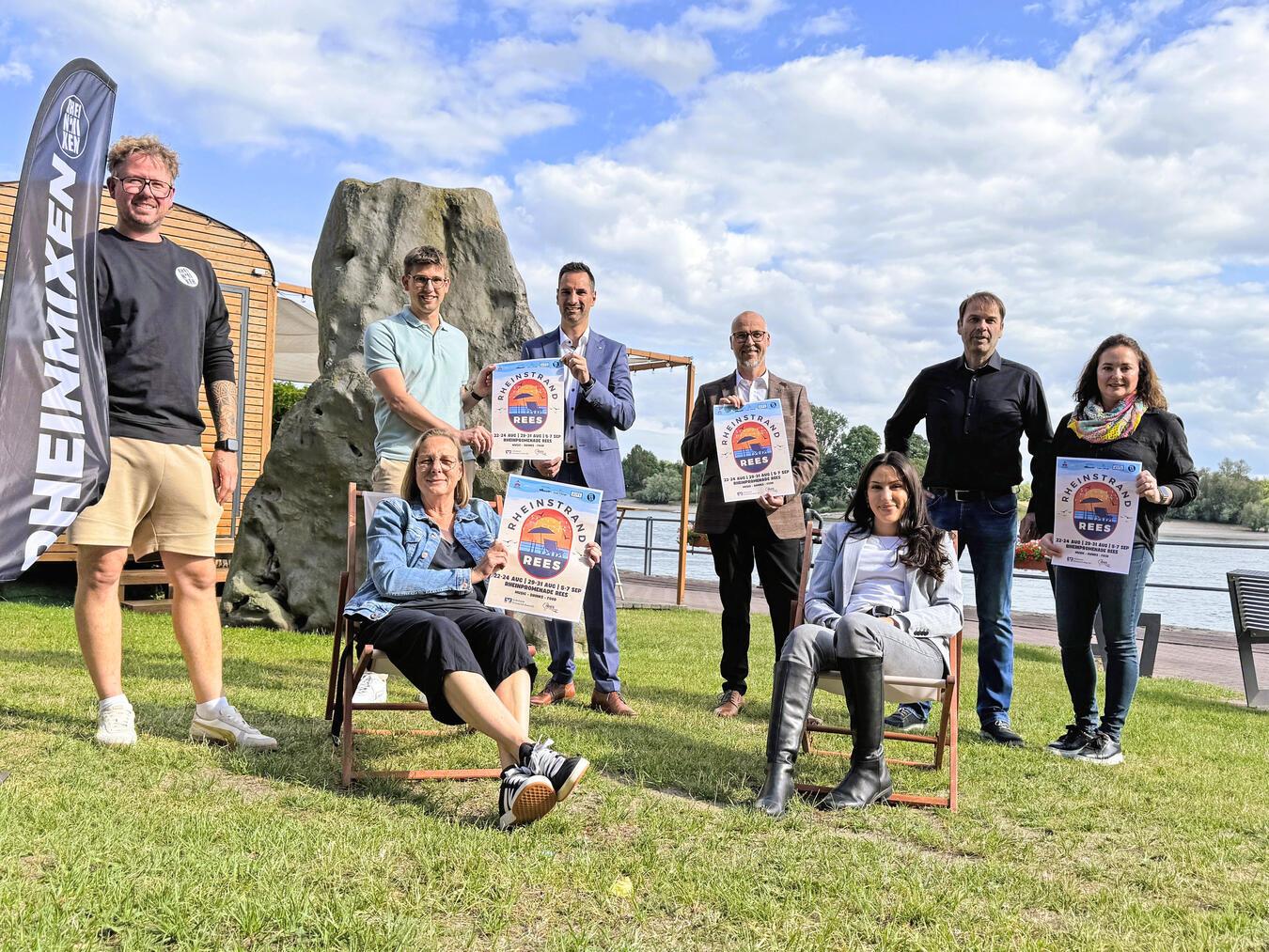 Machen die Reeser Promenade für seine Bürger urlaubstauglich: (vorne v.l.) Claudia Börgers (Stadt), Melina Tenbruck (Marissa Lake Village), (hinten v.l.) Martin van Laak, Jörn Franken (Stadt), Peter Schau (Volksbank Emmerich-Rees), Dirk Krämer (Westenergie) sowie Rainer und Tessa van Straalen (Cafébar 837,5). Foto: Ole Engfeld/Stadt Rees