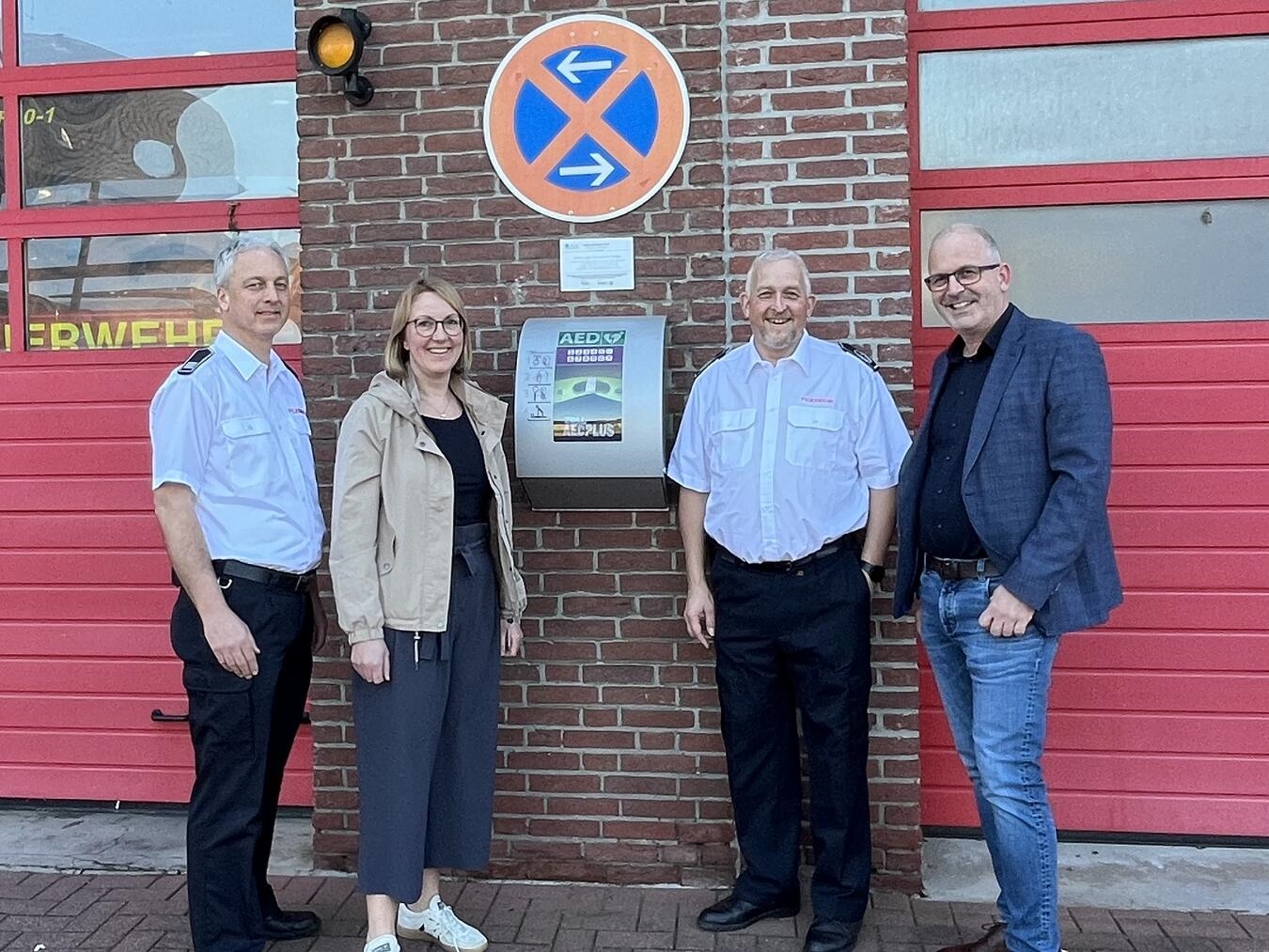 Mario Leupers (Stadtbandinspektor der Feuerwehr Straelen), Anne Teller-Weyers Regionalmanagement (Leader-Region Leistende Landschaft), Thorsten Fischer (Wehrleitung) und Christian Hinkelmann (Fachbereichsleiter Stadt Straelen) vor dem AED am Feuerwehrhaus Herongen. Foto: Stadt Straelen