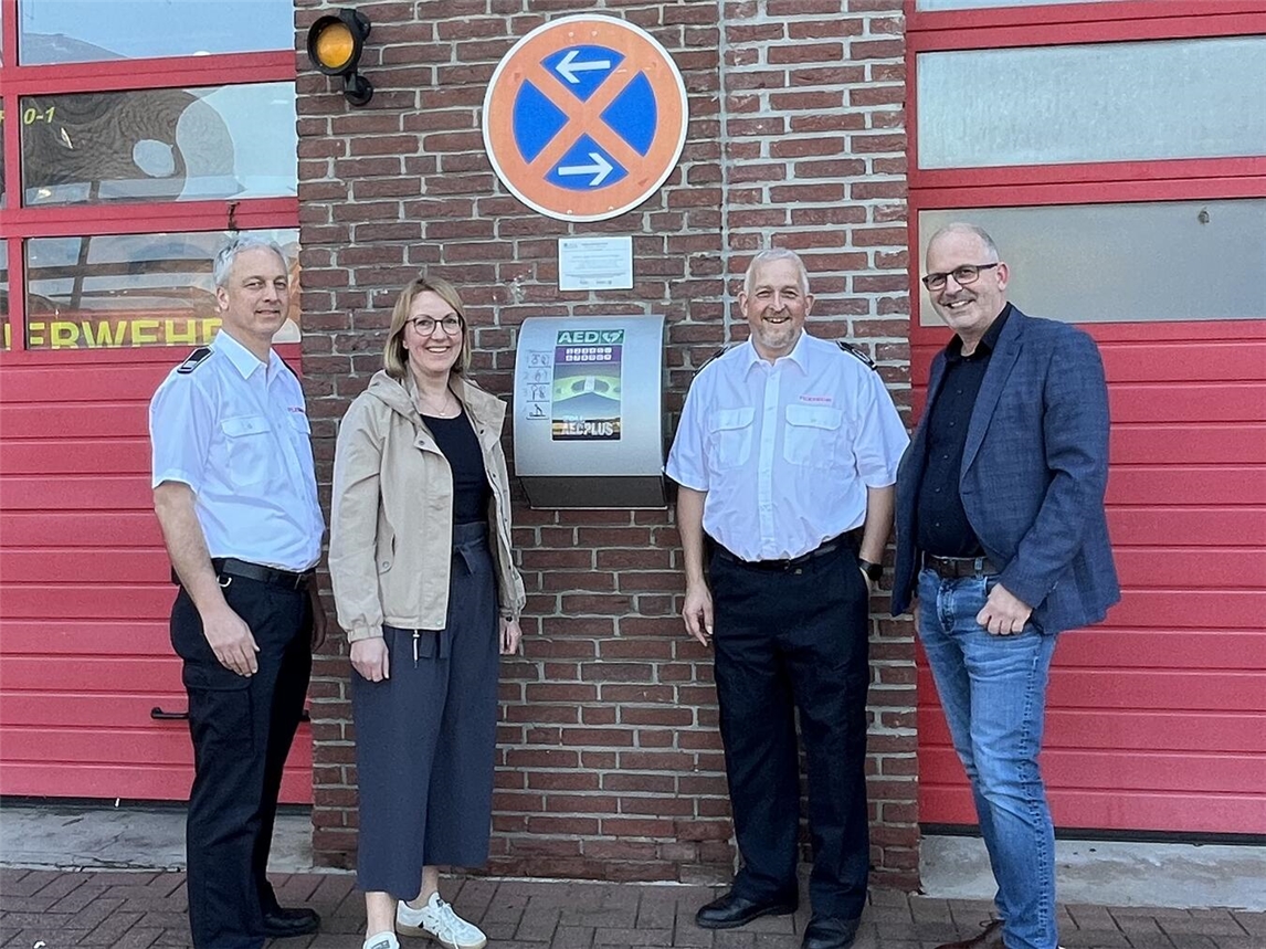 Mario Leupers (Stadtbandinspektor der Feuerwehr Straelen), Anne Teller-Weyers Regionalmanagement (Leader-Region Leistende Landschaft), Thorsten Fischer (Wehrleitung) und Christian Hinkelmann (Fachbereichsleiter Stadt Straelen) vor dem AED am Feuerwehrhaus Herongen. Foto: Stadt Straelen