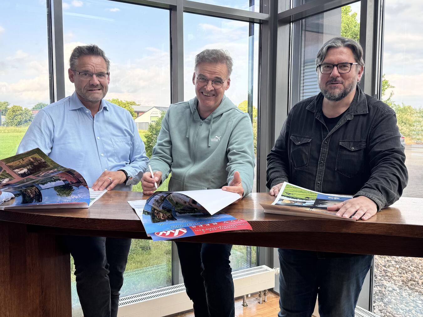 Michael Arts-Meulenkamp (Vorsitzender des VVV, l.) und Michael Scholten (stellvertretender Vorsitzender) besprechen mit Fotograf Axel Breuer die VVV-Kalender der letzten Jahre. Foto: VVV/Dirk Kleinwegen