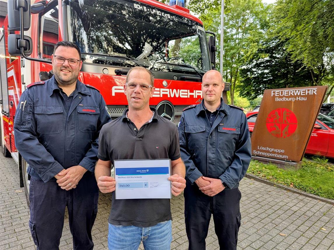 Michael Erren, Dirk Peekel und Tobias van Koeverden (v.l.) bei der symbolischen Scheckübergabe vor den Einsatzfahrzeugen der Löscheinheit Schneppenbaum. Foto: Feuerwehr Bedburg-Hau