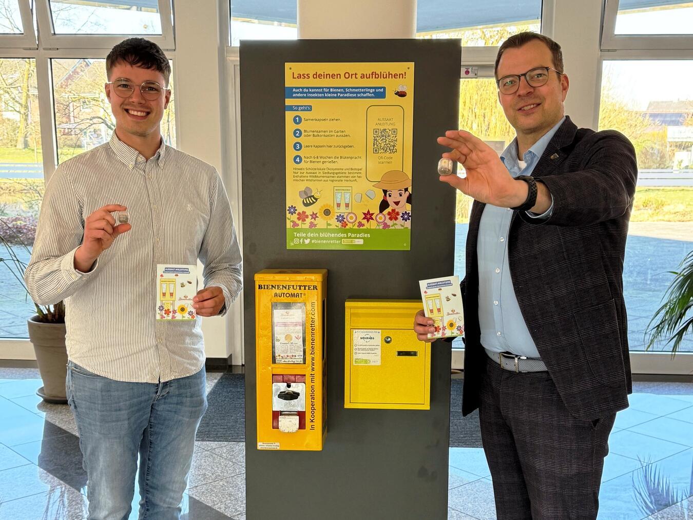 Blumensamen statt Kaugummi Michel Hebing, zuständiger Mitarbeiter im Rathaus und Bürgermeister Stephan Reinders (rechts) präsentieren die aus dem Automaten erhältlichen Kapseln mit den insektenfreundlichen Blühmischungen. Foto: Gemeinde Bedburg-Hau