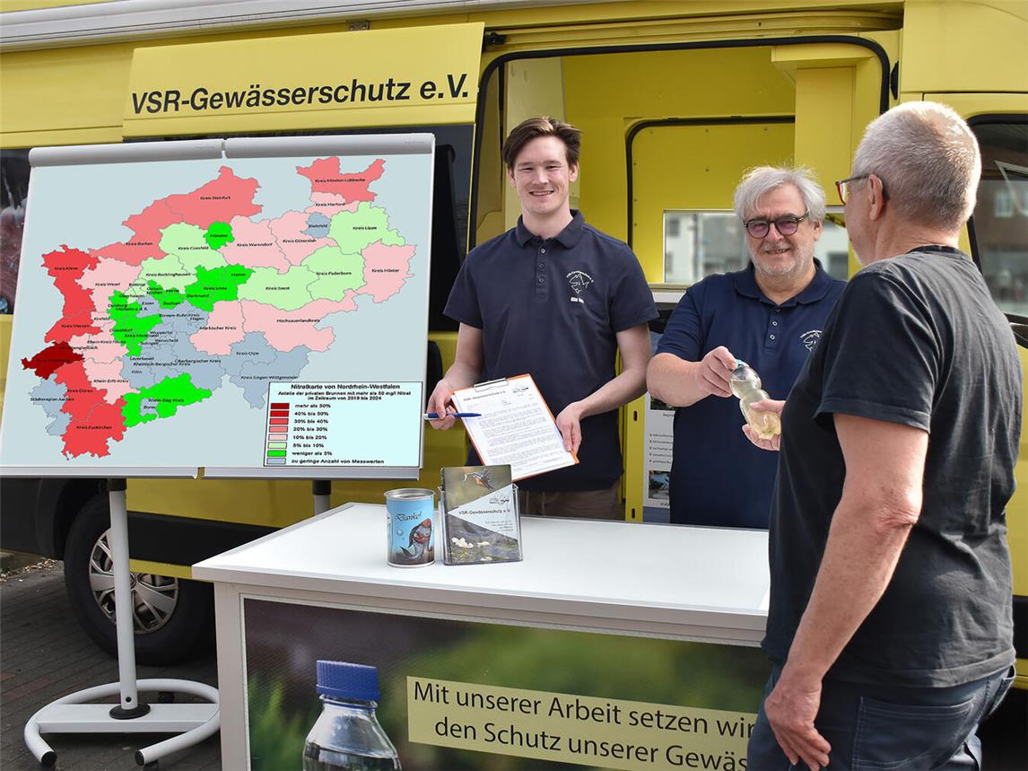 Milan Toups (l.) und Helmut Hartmann (r.) beraten einen Brunnenbesitzer mit Nitratkarte NRW am Labormobil des VSR-Gewässerschutzes. Foto: Ruben Wiltsch