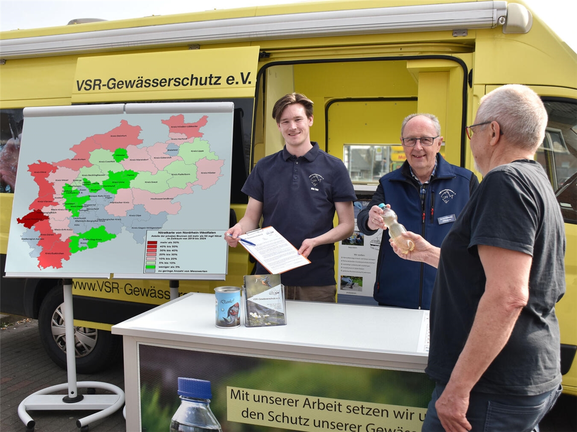 Milan Toups und Heinz-Wilhelmm Hülsmans beraten Brunnenbesitzer am VSR-Gewässerschutz-Labormobil mit Nitratkarte NRW.