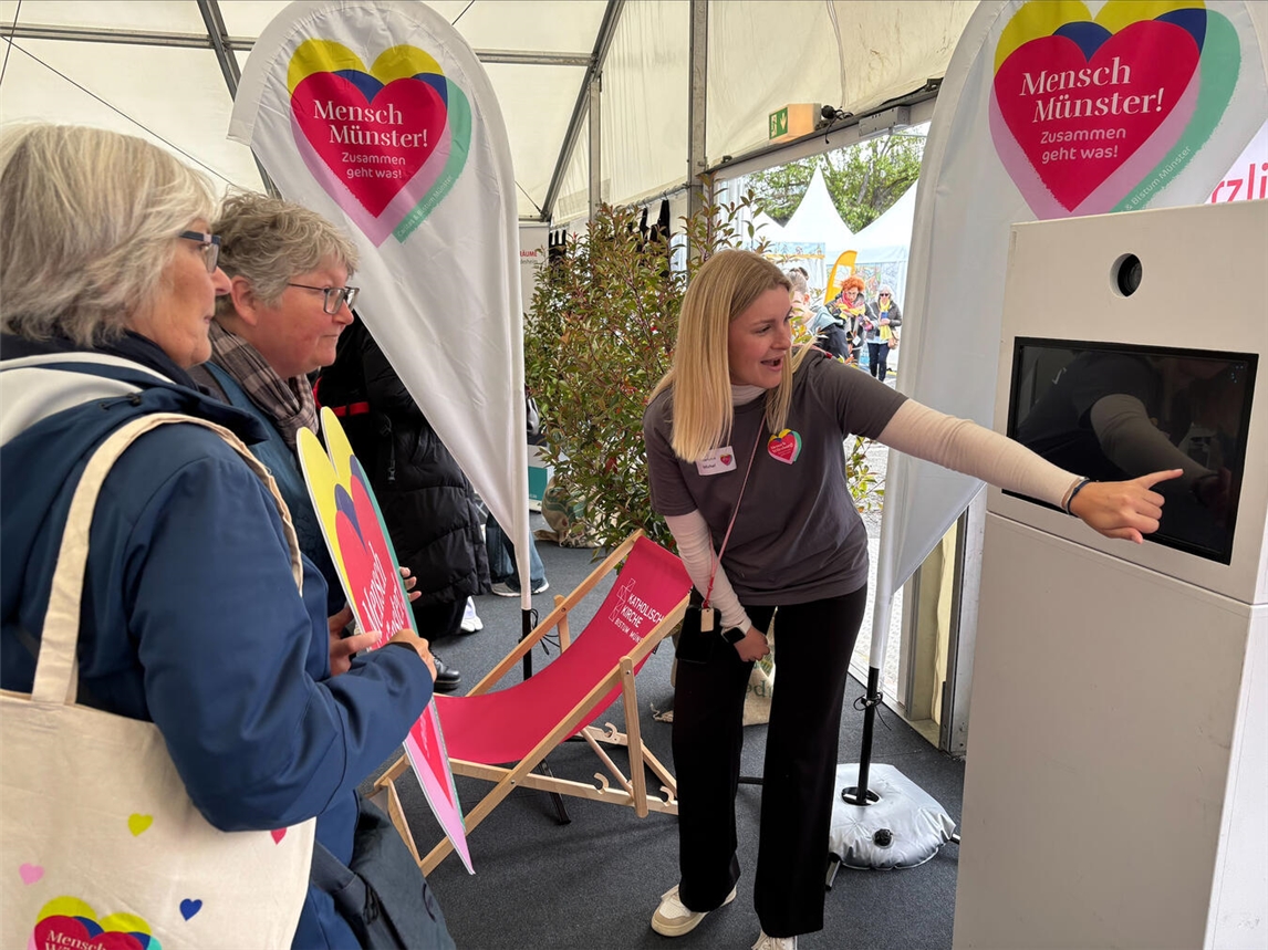 "Team am Bistum Münster Stand mit Fotobox, Marleen Michel begrüßt Besucher, sieben Personen, Foto: Bischöfliche Pressestelle/Anke Lucht"